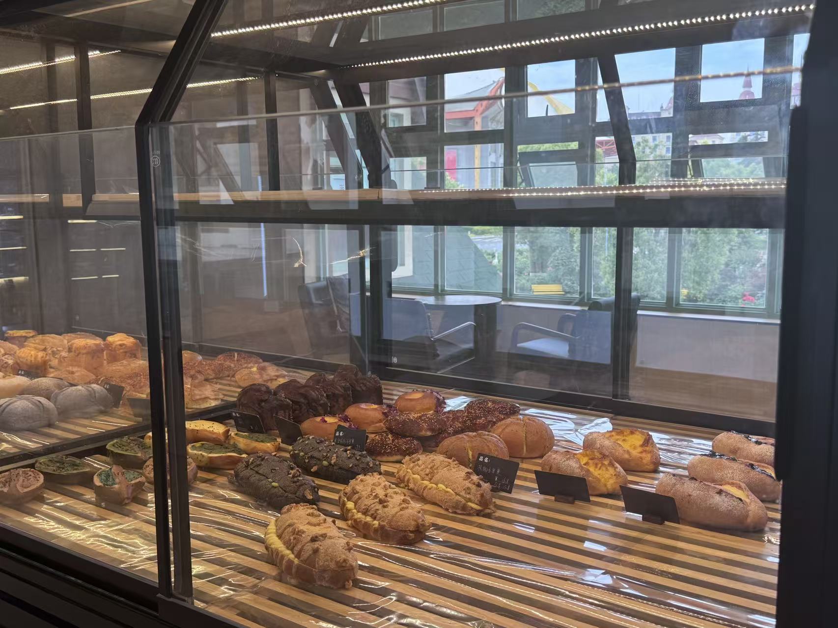 Warm Wheat pastry case with sweet breads, tarts, and filled buns.