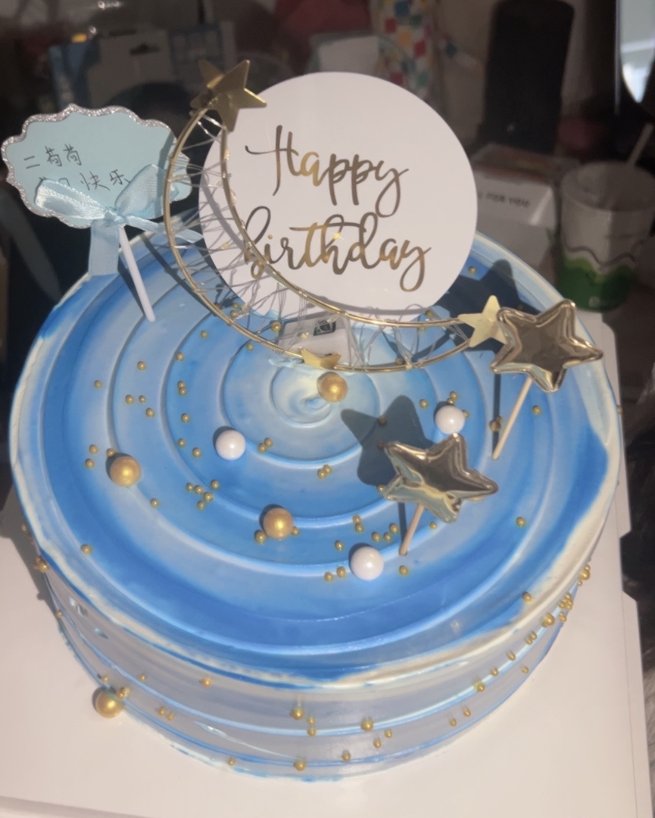 Dreamy blue starry sky cake with gold decorations and birthday topper.